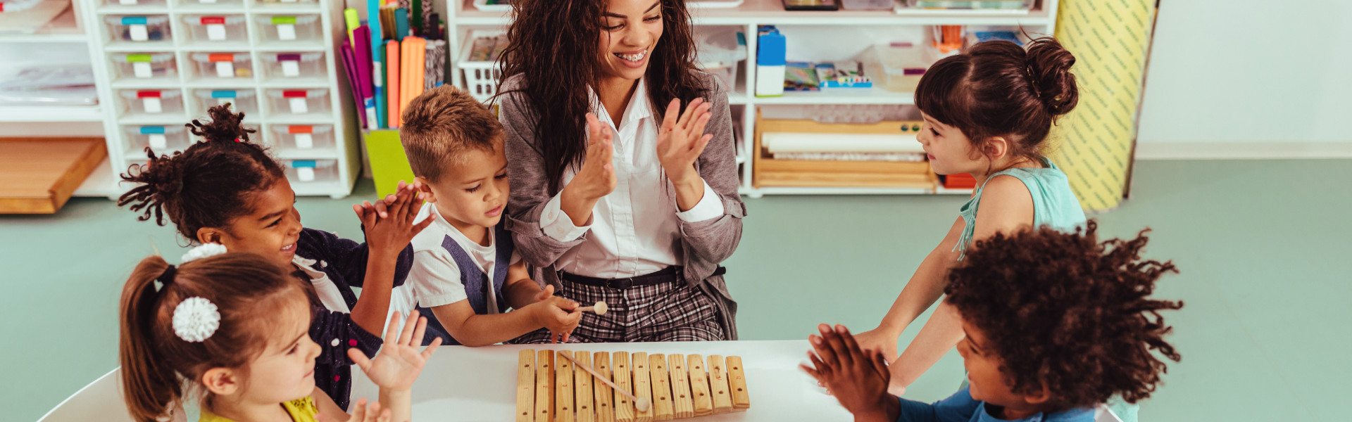 Teacher and diverse preschool boys and girls playing musical toys
